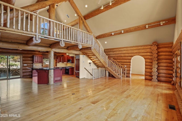 unfurnished living room with visible vents, stairs, high vaulted ceiling, beamed ceiling, and light wood-type flooring