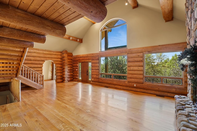 unfurnished living room featuring beamed ceiling, wood-type flooring, log walls, and high vaulted ceiling