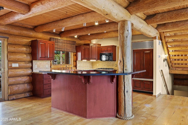 kitchen featuring dark brown cabinets, light wood-style flooring, a breakfast bar, paneled refrigerator, and black microwave