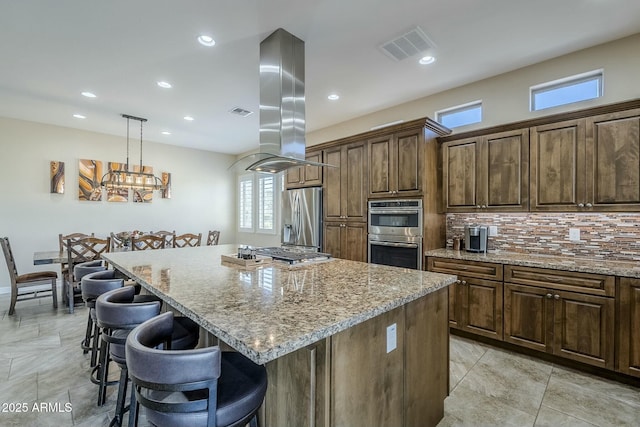 kitchen featuring pendant lighting, a breakfast bar area, a kitchen island, stainless steel appliances, and island exhaust hood