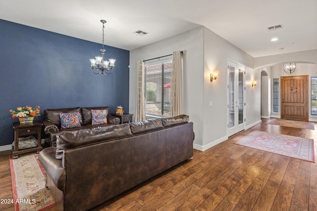 living room featuring dark hardwood / wood-style floors, french doors, and an inviting chandelier