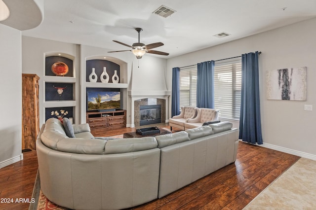 living room featuring built in shelves, dark hardwood / wood-style floors, and ceiling fan