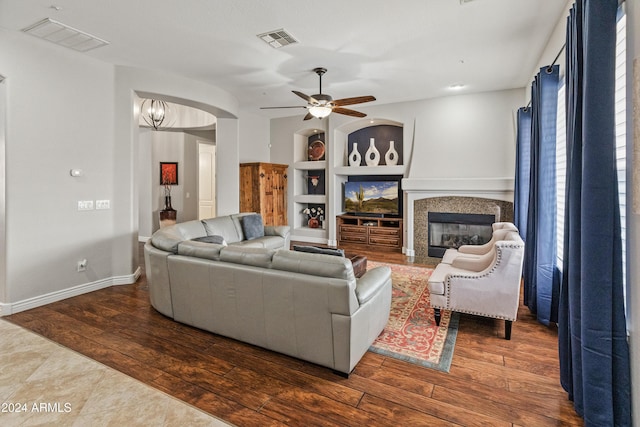 living room featuring built in shelves, dark hardwood / wood-style flooring, and ceiling fan with notable chandelier