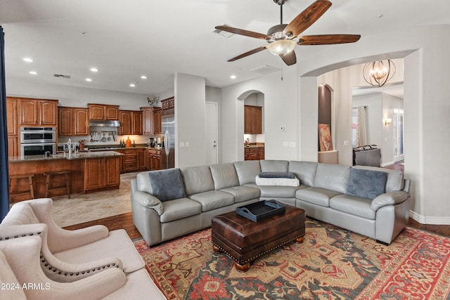 living room with ceiling fan with notable chandelier and light hardwood / wood-style flooring