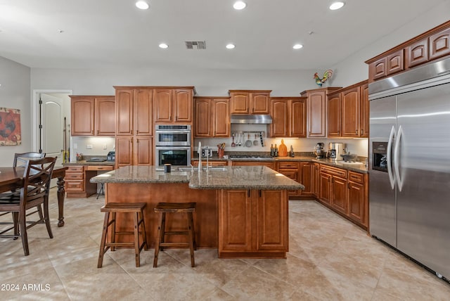 kitchen with a breakfast bar, a kitchen island with sink, sink, light tile patterned floors, and appliances with stainless steel finishes