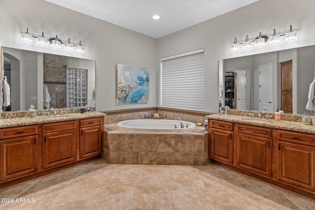 bathroom featuring tiled tub, tile patterned flooring, and vanity