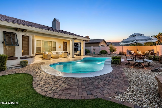 pool at dusk featuring outdoor lounge area and a patio