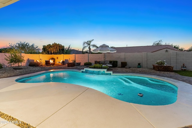 pool at dusk with pool water feature and a patio