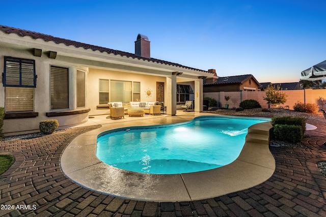 pool at dusk featuring an outdoor living space and a patio area