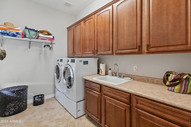 washroom with cabinets, light tile patterned floors, sink, and washing machine and dryer