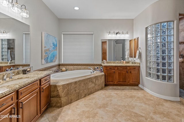 bathroom featuring tile patterned floors, vanity, and tiled bath