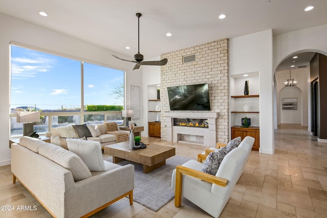 living room with built in shelves, ceiling fan, and a large fireplace