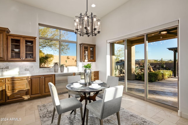 dining area with a towering ceiling, an inviting chandelier, and a healthy amount of sunlight