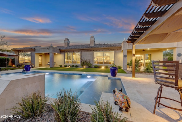 pool at dusk with ceiling fan, a patio area, and a pergola