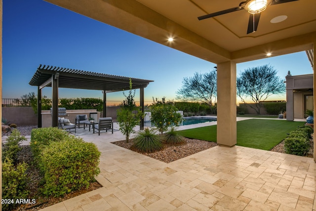 patio terrace at dusk featuring a pergola, ceiling fan, exterior kitchen, a fenced in pool, and a lawn