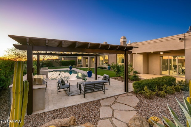 patio terrace at dusk featuring outdoor lounge area, exterior kitchen, and a pergola