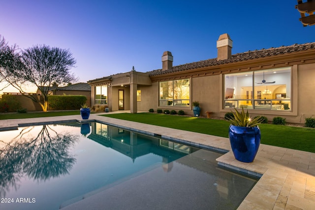 back house at dusk with a yard and a patio