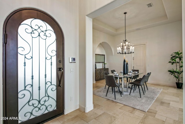 foyer with a chandelier and a raised ceiling