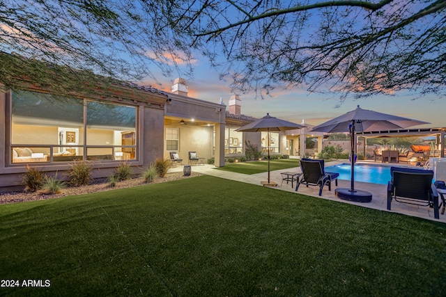 yard at dusk with ceiling fan and a patio