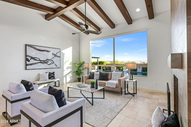 living room with beamed ceiling, ceiling fan, a large fireplace, and high vaulted ceiling