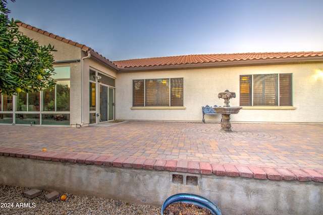 back house at dusk featuring a patio area