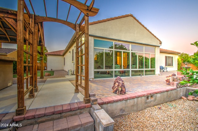 back house at dusk with a patio and a pergola