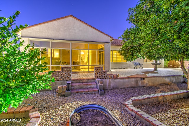 back of house featuring a sunroom, a patio, and a fire pit