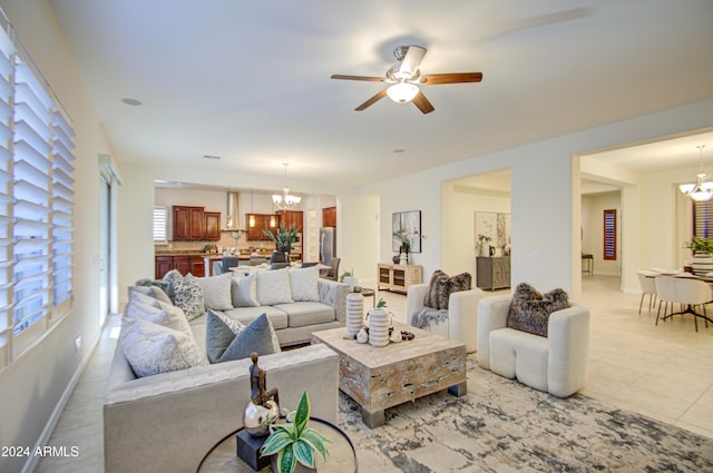 living room featuring light tile patterned flooring and ceiling fan with notable chandelier