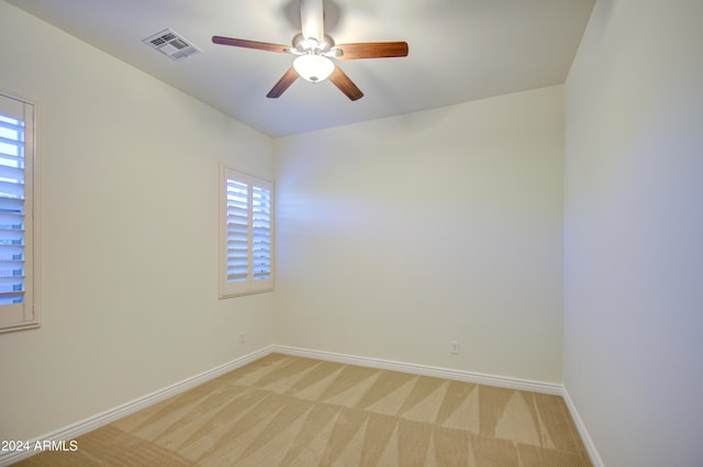 empty room featuring ceiling fan and light colored carpet