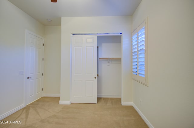 unfurnished bedroom with light carpet and a closet