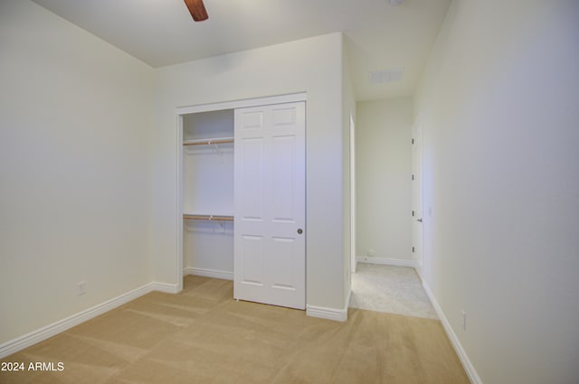 unfurnished bedroom with light colored carpet, ceiling fan, and a closet