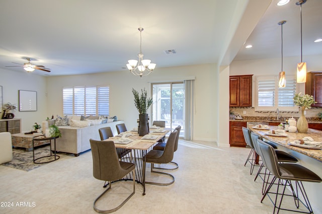 dining area featuring sink, a healthy amount of sunlight, and ceiling fan with notable chandelier