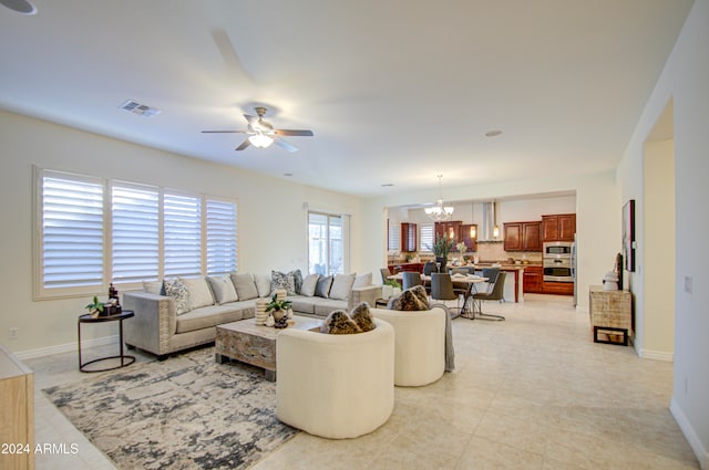 tiled living room featuring ceiling fan with notable chandelier