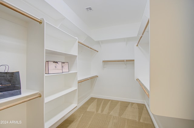 walk in closet featuring light colored carpet