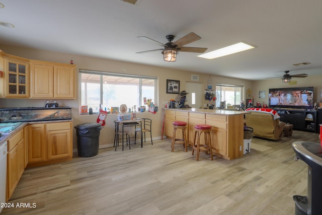 kitchen with a kitchen breakfast bar, ceiling fan, and light hardwood / wood-style floors