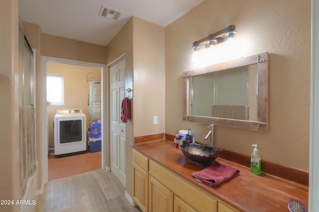 bathroom with hardwood / wood-style floors, vanity, and washer / dryer