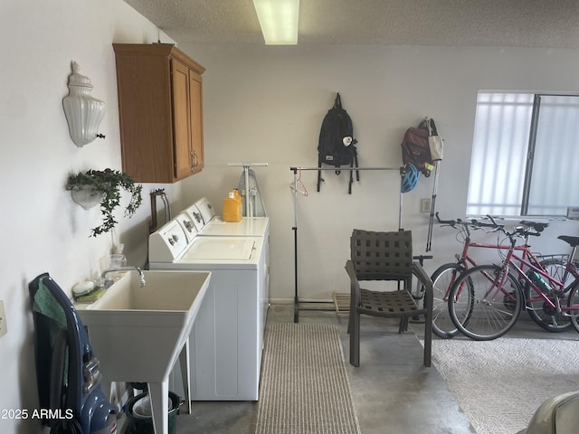 clothes washing area with cabinet space, independent washer and dryer, a textured ceiling, and a sink