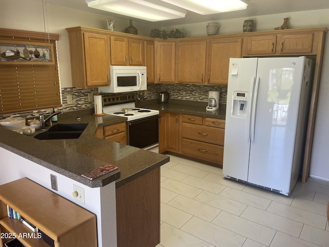 kitchen featuring dark countertops, white appliances, decorative backsplash, and a sink