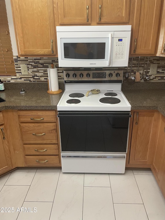 kitchen featuring brown cabinets, range with electric stovetop, decorative backsplash, and white microwave