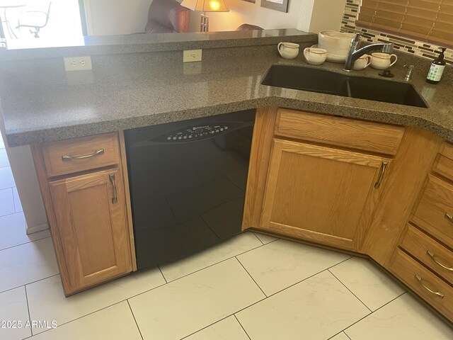 kitchen featuring black dishwasher, brown cabinets, and a sink