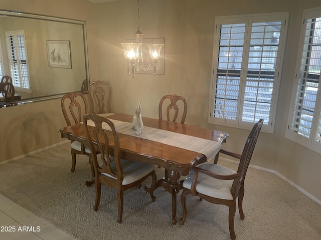 dining room featuring baseboards, carpet floors, tile patterned floors, and an inviting chandelier