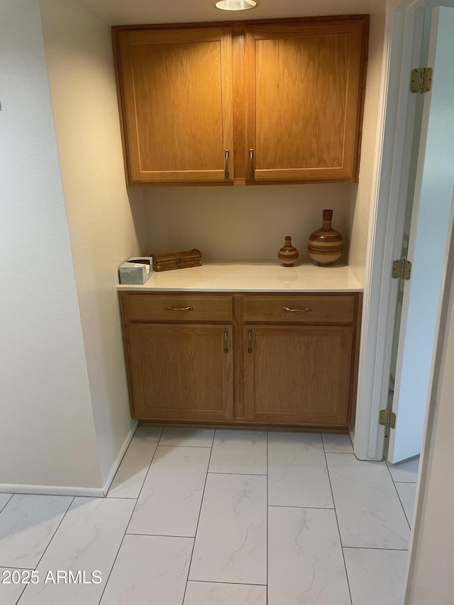 kitchen with marble finish floor, brown cabinets, and light countertops