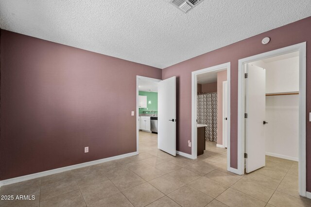 1120 N Val Vista Dr Unit 110, Gilbert, AZ 85234 - unfurnished bedroom featuring light tile patterned floors, a textured ceiling, a spacious closet, a closet, and baseboards