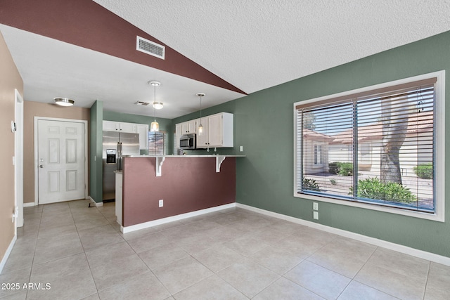 1120 N Val Vista Dr Unit 110, Gilbert, AZ 85234 - kitchen featuring appliances with stainless steel finishes, lofted ceiling, a peninsula, white cabinetry, and a textured ceiling