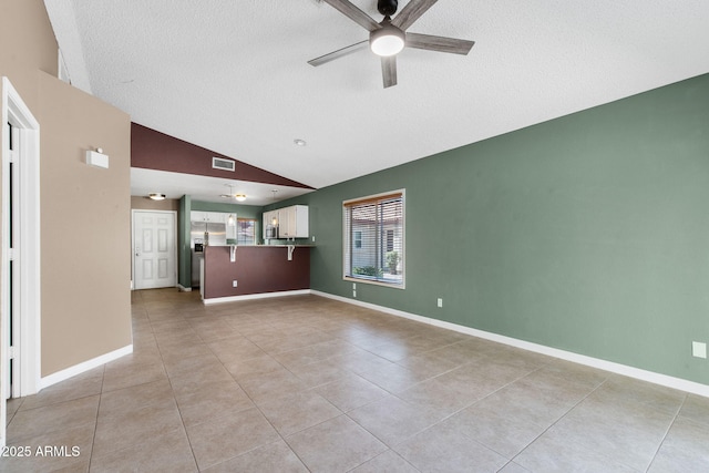 1120 N Val Vista Dr Unit 110, Gilbert, AZ 85234 - unfurnished living room with a ceiling fan, a textured ceiling, light tile patterned flooring, vaulted ceiling, and baseboards