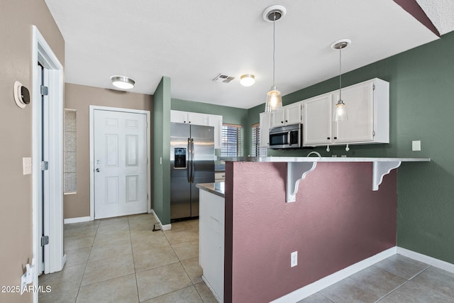 1120 N Val Vista Dr Unit 110, Gilbert, AZ 85234 - kitchen with appliances with stainless steel finishes, a peninsula, white cabinets, a kitchen bar, and pendant lighting