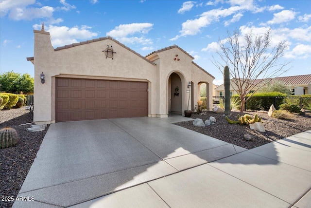 mediterranean / spanish-style home with a garage, driveway, fence, and stucco siding