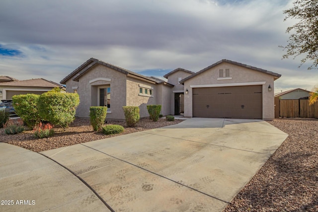 ranch-style house with concrete driveway, a tile roof, an attached garage, fence, and stucco siding