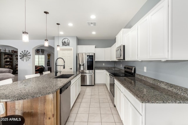 kitchen with arched walkways, a sink, visible vents, white cabinetry, and appliances with stainless steel finishes