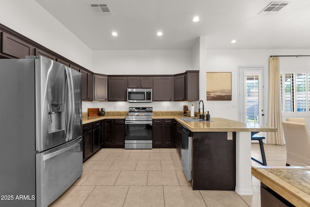 kitchen with a sink, appliances with stainless steel finishes, a peninsula, and visible vents